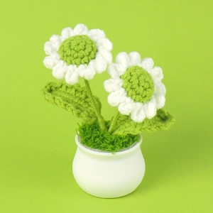 Close-up of handmade crochet white daisy plant in a small white pot with green leaves
