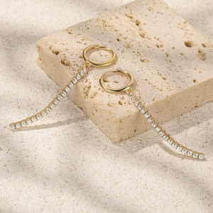 Detail of gold S925 silver earrings with long tassel tennis chain and sparkling zircons