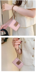 Detail of pink embossed leather wallet with wrist strap and metal logo plaque