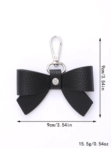 Detail showing black leather bow keychain with silver metal clasp and a crystal rhinestone