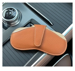 Close-up of orange-brown litchi grain leather glasses pouch inside a car interior