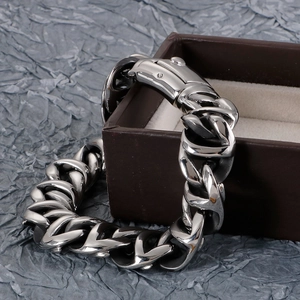 Detail of silver bold cuban link bracelet with square clasp on brown gift box