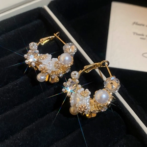 Close-up of pearl flower earrings with sparkling rhinestones on a black velvet base