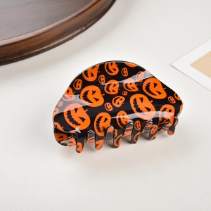Close-up of Halloween shark hair clip featuring orange pumpkins on black glossy resin