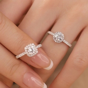 Gros plan de deux bagues en diamant halo avec coupes rondes et coussin sur une main