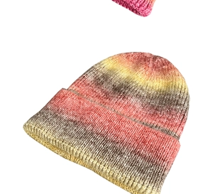 Macro shot of chunky knit texture and colorful tie-dye gradient on the winter beanie