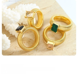 Close-up of gold-plated geometric gemstone rings on marble for elegant jewelry display