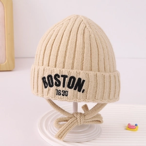 Close-up of beige knit baby hat featuring vertical texture and BOSTON letter embroidery