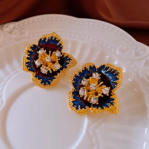 Macro detail of vintage blue enamel flower earrings with gold edges and rhinestones