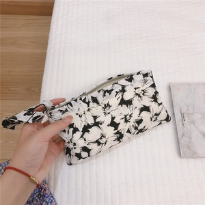 Détail du mini sac en tissu floral avec fermeture éclair et dragonne sur fond matelassé