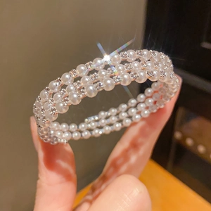 Detailed macro view of triple-layered pearl and rhinestone bracelet with shimmering effect