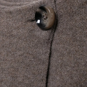 Close-up of brown wool texture and dark resin button on a knitted scarf cloak coat