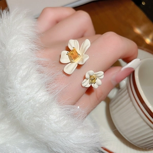 Detail of gold plated flower ring with white petals and yellow gemstone on model finger