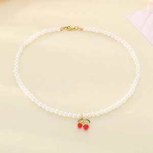 Detail of pearl necklace featuring a red cherry pendant with golden lobster clasp closure