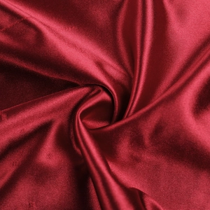 Dettaglio macro del tessuto in raso rosso di un abito con pieghe e finitura lucida