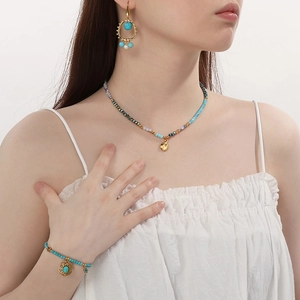 Close-up of bohemian turquoise jewelry set with tassel earrings and beaded necklace on model