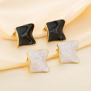 Macro shot of irregular square enamel earrings in black and white marble on satin