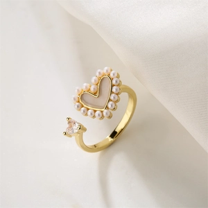 Détail d'une bague coeur dorée avec bordure en perles et pierre de zircon