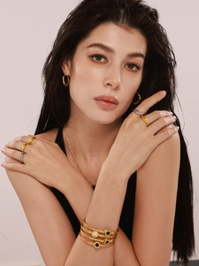 Close-up of gold cable twist bracelet and ring with black onyx and mother of pearl