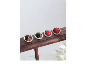 Close-up of retro round earrings set with tiger eye and red stone in rope silver frames