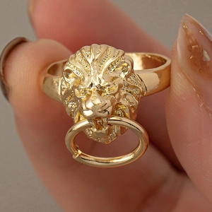 Golden lion head ring with a movable door knocker ring held between fingertips