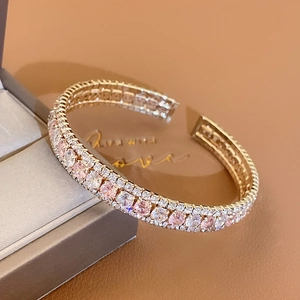 Gros plan d'un bracelet jonc à trois rangées de zircons roses et blancs en or rose