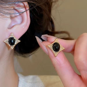 Close-up of vintage gold star stud earrings with black oval stone inlay on ear lobe