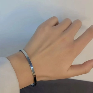 Sleek silver stainless steel open bangle with a polished finish worn on a wrist