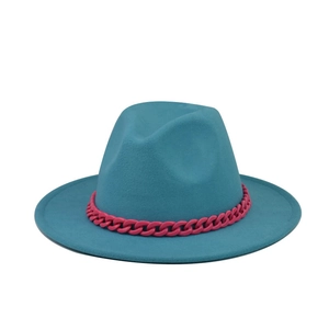 Detailed close-up of a peacock blue wool fedora hat with a bold pink chain strap detail