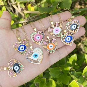 Macro detail of heart-shaped evil eye pendants with colorful zircon inlay in gold