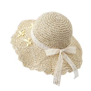 Beige woven straw sun hat with white lace ribbon and yellow checkered bows on white backdrop