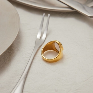 Detail of 18K gold stainless steel ring with white pearl on elegant textured white fabric