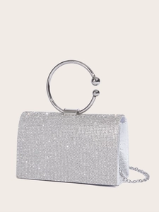 Close-up of silver evening clutch bag with sparkling rhinestones and metal ring handle