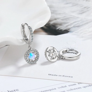 Macro shot of S925 sterling silver opal earrings with zircon border on white ceramic