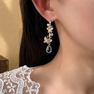 Elegant gold butterfly earrings with blue teardrop gemstone on female model