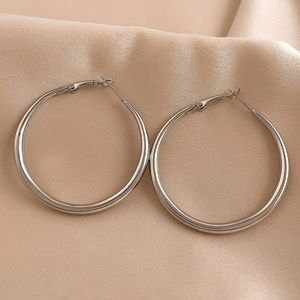 Detailed view of polished silver hoop earrings on elegant pink silk satin fabric