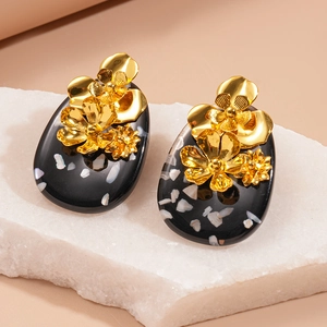Vintage oval resin earrings with gold flowers and white shells on a quartz block