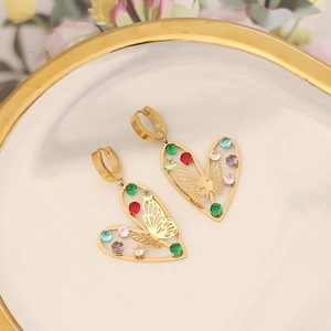 Golden heart earrings with butterfly design and colorful cubic zirconia on ceramic plate
