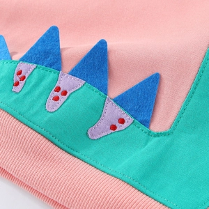Close-up of pink cotton kids dinosaur sweatshirt featuring green felt and blue back fins