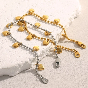 Close-up of 18K gold and silver beaded heart bracelets on a textured stone surface