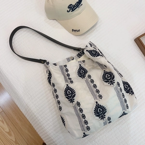 Off-white cotton linen tote bag with blue ethnic embroidery and black shoulder straps