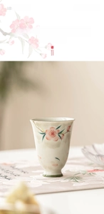 Detailed view of hand-painted peach blossom pattern on a ceramic high-foot tea cup