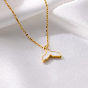 Macro detail of golden fishtail pendant necklace with white shell inlay on white satin