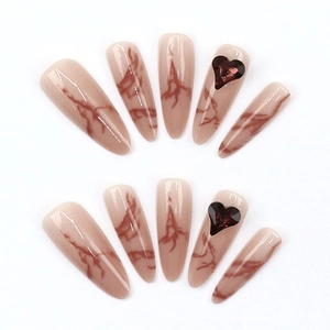 Long almond press-on nails with brown marble patterns and 3D heart-shaped jewels