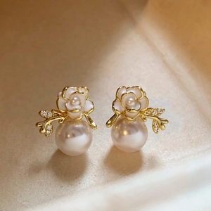 Detailed macro view of gold-plated flower stud earrings with elegant pearls and zircons