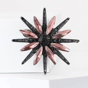Detailed view of an eight-pointed star brooch with pink crystals on a dark metal base