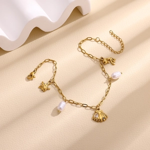 Detail of gold starfish and shell charms with pearls on a textured background