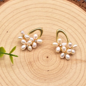 Macro detail of 925 silver pearl earrings in floral design on a natural wood surface