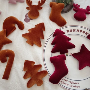 Macro detail of velvet Christmas ornaments including tree and star on white linen