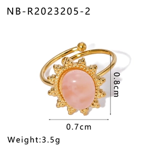 Detail shot of golden adjustable ring with pink oval stone and sunburst metal decor